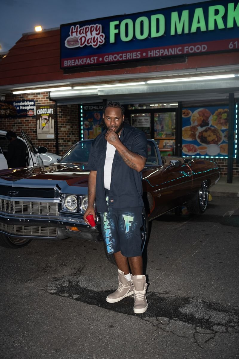 Stizzle f standing beside a classic car outside Happy Days Food Market at dusk